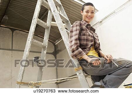 Female interior decorator sitting on ladder in work site, portrait, low angle view View Large Photo Image Stock Image - Female interior decorator sitting on ladder in work site, portrait, low angle view. Fotosearch