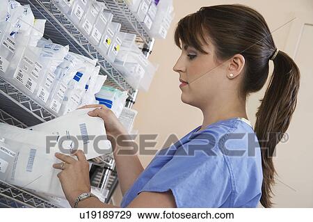 Female nurse standing at shelf with medicinal supplies View Large Photo Image Stock Photo - Female nurse standing at shelf with medicinal supplies. Fotosearch