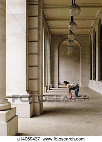 Female runner crouching in starting position in portico, side view View Large Photo Image Stock Photo - Female runner crouching in starting position in portico, side view. Fotosearch