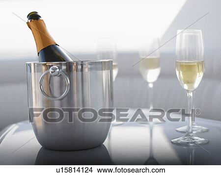 Picture - Flutes and champagne in ice bucket on table. Fotosearch