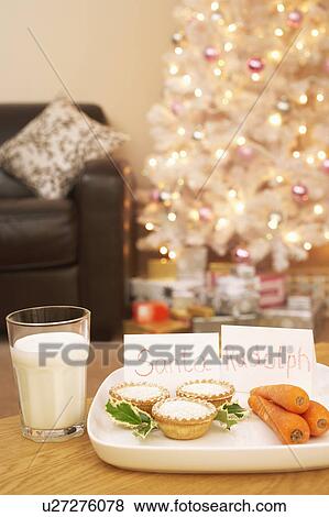 Stock Photo - Food for Santa and Rudolph near Christmas tree in home. Fotosearch