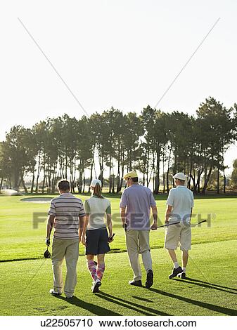 Stock Image - Four young golfers walking on course, back view. Fotosearch