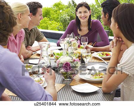 Friends eating, drinking and socialising at table outdoors View Large Photo Image Picture - Friends eating, drinking and socialising at table outdoors. Fotosearch