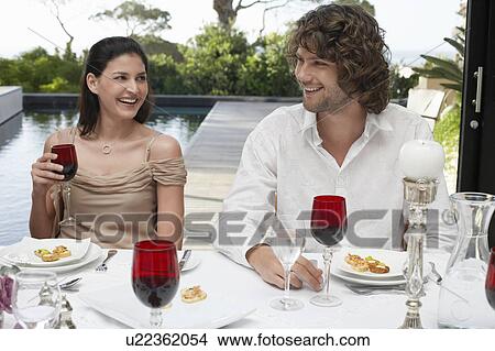 Picture - Friends sitting outside, near pool, socialising at Dinner Party. Fotosearch