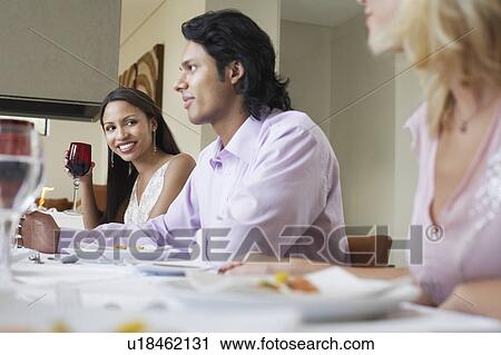 Stock Image - Friends sitting together at Dinner Party. Fotosearch