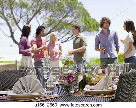 Friends standing outside, drinking, near a set table View Large Photo Image Stock Image - Friends standing outside, drinking, near a set table . Fotosearch