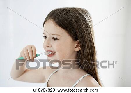 Stock Photo - Girl Brushing Teeth in bathroom, close up. Fotosearch