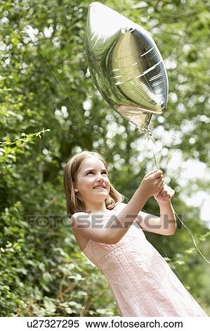 Stock Photography - Girl in park playing in park with helium filled balloon. Fotosearch