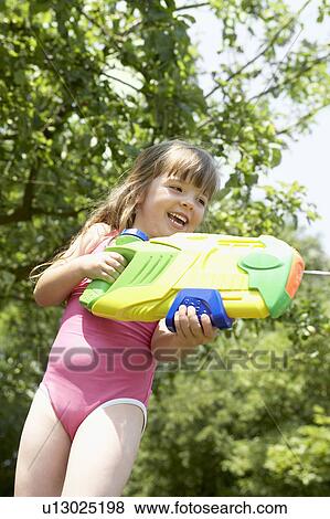 Stock Photo - Girl in park shooting pump action water pistol. Fotosearch