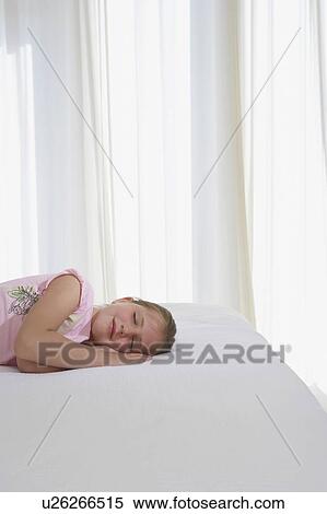 Stock Photography - Girl sleeping on bed, half length. Fotosearch