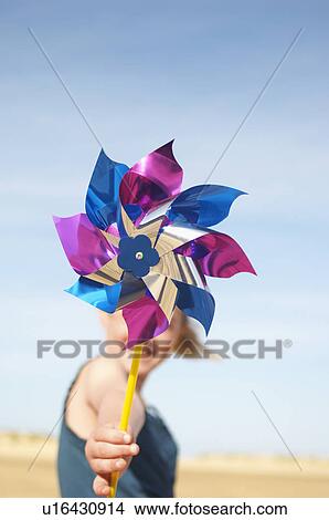 Picture - Girl standing on beach holding pinwheel, close up of pinwheel. Fotosearch