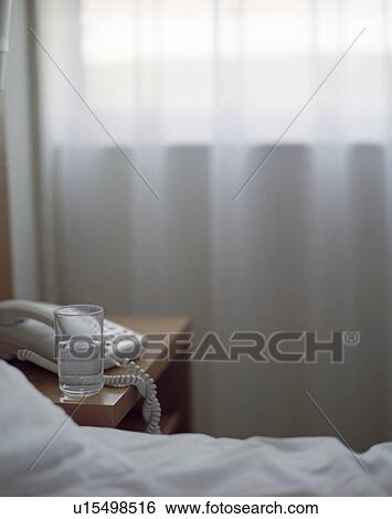 Stock Photograph - Glass of Water on Nightstand in Hotel Room. Fotosearch