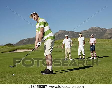 Golfer putting green, friends in background View Large Photo Image Stock Photo - Golfer putting green, friends in background. Fotosearch