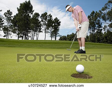 Stock Photo - Golfer putting, low angle view. Fotosearch