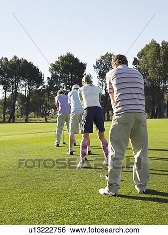 Golfers teeing off, back view View Large Photo Image Stock Photograph - Golfers teeing off, back view. Fotosearch