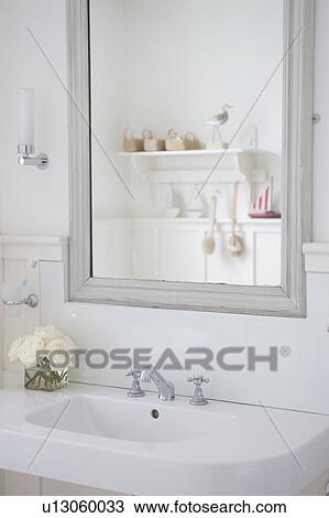 Stock Image - Grey painted mirror surround above washbasin, London. Fotosearch