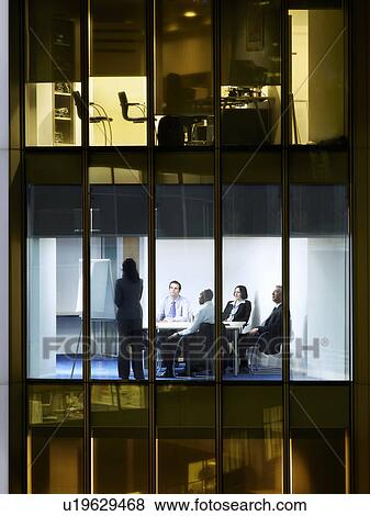 Group of business people at meeting in office, view from building exterior View Large Photo Image Stock Photo - Group of business people at meeting in office, view from building exterior. Fotosearch