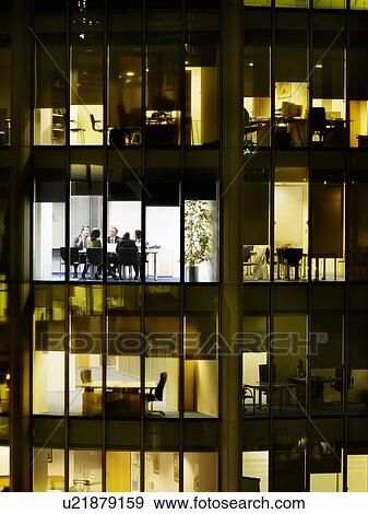 Stock Photo - Group of business people at meeting in office, view from building exterior. Fotosearch