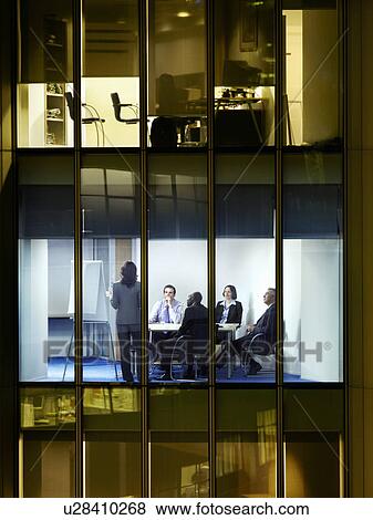 Stock Photo - Group of business people at meeting in office, view from building exterior. Fotosearch