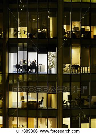 Stock Photograph - Group of business people at meeting in office, view from building exterior. Fotosearch