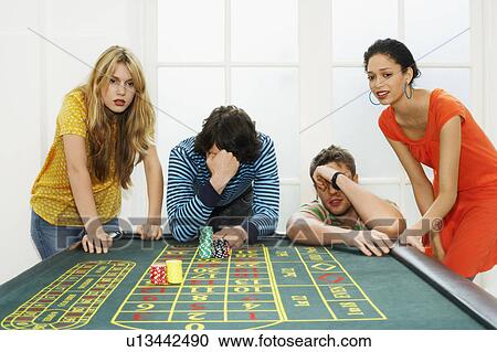 Stock Image - Group of friends losing on roulette table. Fotosearch