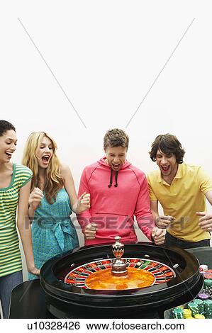 Stock Photograph - Group of friends winning on roulette wheel. Fotosearch