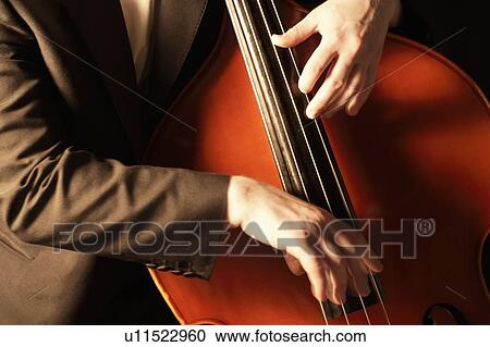 Stock Image - HaNds plucking fingerboard of double bass. Fotosearch