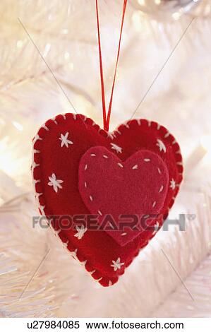 Stock Photography - Heart shaped decoration hanging on Christmas tree, close-up. Fotosearch