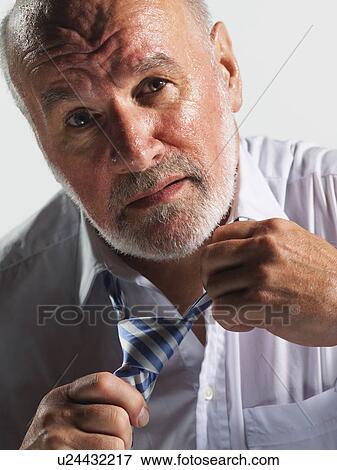 Stock Photo - Hot businessman loosening tie, close-up. Fotosearch