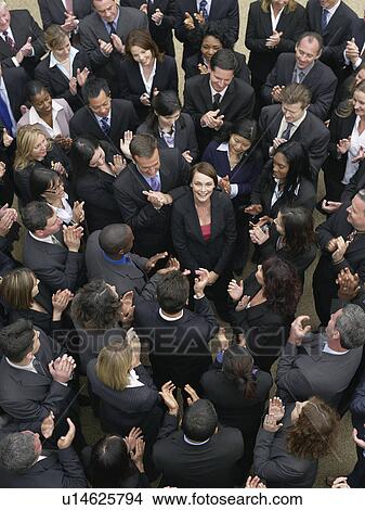 Picture - Large group of business people clapping, surrounding woman looking up, elevated view. Fotosearch