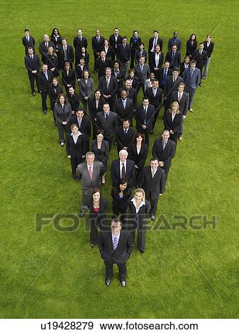 Stock Photo - Large group of business people standing in triangle formation, elevated view. Fotosearch