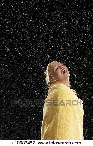 Stock Image - Laughing Woman Wrapped in Towel Standing in Rain. Fotosearch