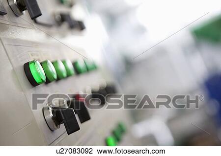 Stock Image - Lit lights and control dials on manufacturing machinery. Fotosearch