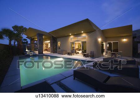 Lit swimming pool and house exterior at night View Large Photo Image Stock Photo - Lit swimming pool and house exterior at night. Fotosearch