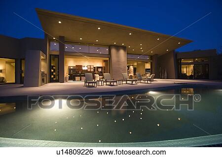 Lit swimming pool and house exterior at night View Large Photo Image Stock Photograph - Lit swimming pool and house exterior at night. Fotosearch