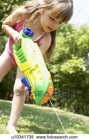 Little girl in park shooting water pistol into grass View Large Photo Image Stock Photography - Little girl in park shooting water pistol into grass. Fotosearch