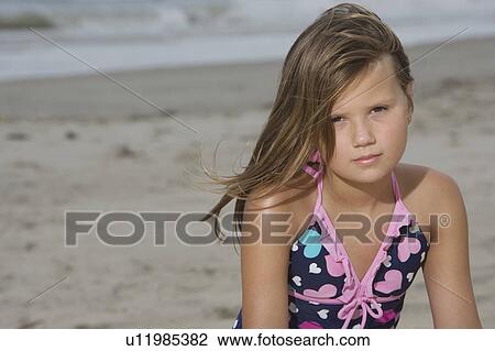 Stock Image - Little Girl Sitting on a Beach. Fotosearch