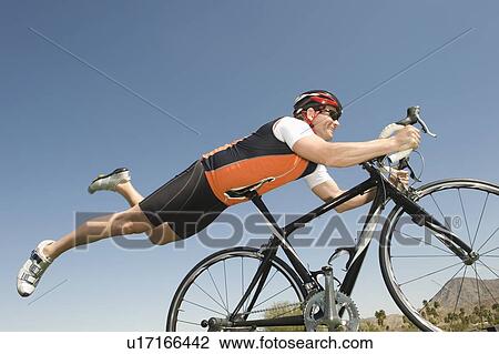 Stock Image - Male cyclist balances his stomach on bicycle seat. Fotosearch