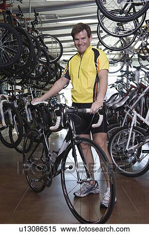 Stock Photography - Male cyclist chooses a new bike. Fotosearch