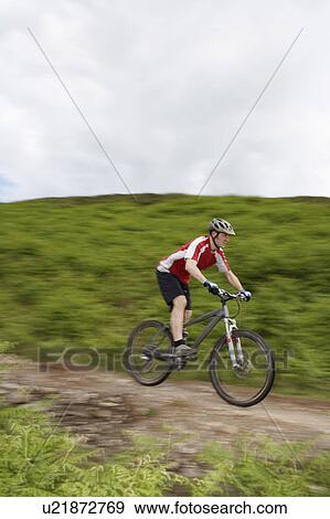 Stock Photo - Male cyclist on track in countryside. Fotosearch