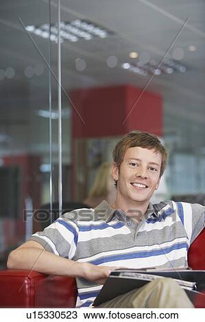 Male office worker sitting on sofa in office, portrait View Large Photo Image Stock Image - Male office worker sitting on sofa in office, portrait. Fotosearch