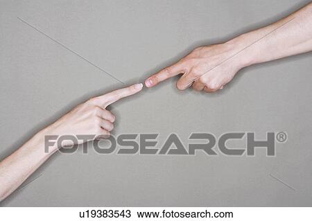 Stock Image - Man and woman almost touching extended index fingers, close-up on arms. Fotosearch