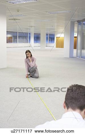 Stock Photo - Man and Woman Measuring New Office Space. Fotosearch