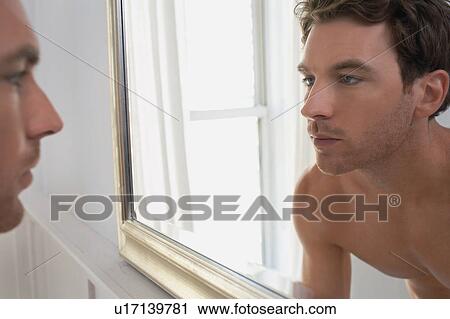 Man examining reflection in mirror View Large Photo Image Stock Image - Man examining reflection in mirror. Fotosearch