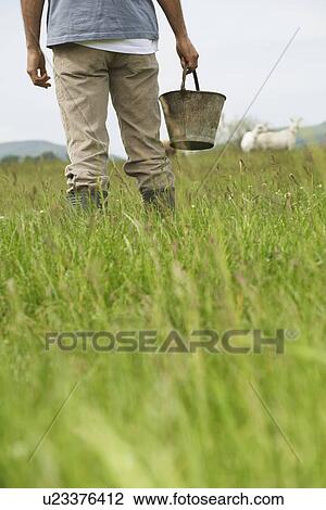 Man holding bucket in field, mid section, rear view View Large Photo Image Stock Image - Man holding bucket in field, mid section, rear view. Fotosearch
