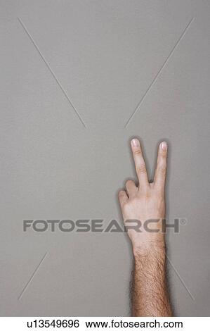 Man holding up two fingers against grey background View Large Photo Image Stock Photograph - Man holding up two fingers against grey background. Fotosearch