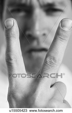 Stock Image - Man holding up two fingers, close-up, black and white. Fotosearch
