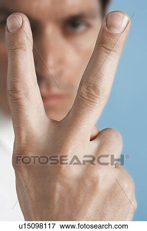 Stock Photo - Man holding up two fingers, close-up. Fotosearch
