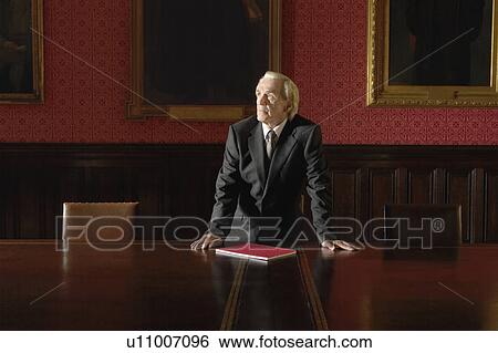 Stock Photograph - Man in Board Room, leaning on table. Fotosearch
