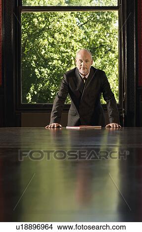 Man leaning on Conference Table, greenery behind View Large Photo Image Picture - Man leaning on Conference Table, greenery behind. Fotosearch